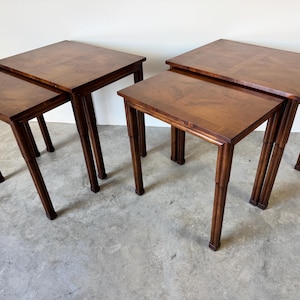 May include: Set of four nesting tables with a dark wood finish. The tables are square and have a simple design.