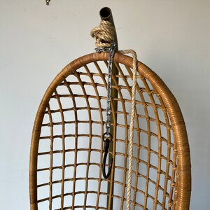 May include: A brown wicker hanging chair with a metal chain and rope hanging from the top.