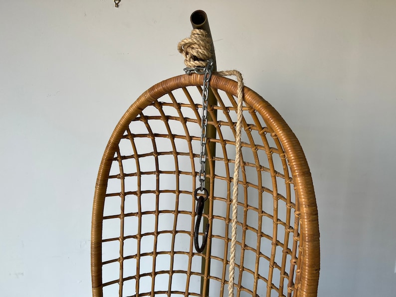 May include: A brown wicker hanging chair with a metal chain and rope hanging from the top.