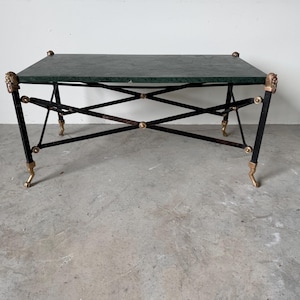 May include: A rectangular coffee table with a dark green marble top. The black metal frame features gold-colored lion head accents and claw feet. The table is approximately 48 inches long and 24 inches wide.