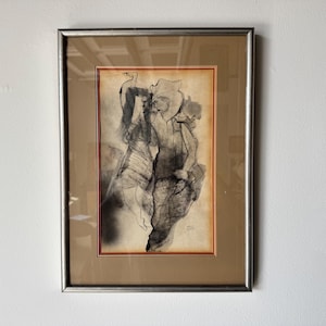 May include: A framed black and white abstract drawing of two figures in a stylized pose. The drawing is on a cream-colored paper with a red border.