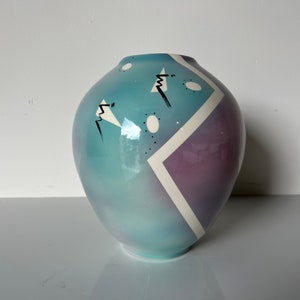 May include: A blue and purple ceramic vase with a geometric design. The vase has a rounded shape and a white glaze.