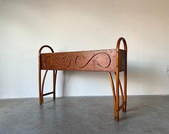May include: A wooden plant stand with a rectangular planter box. The planter box has a decorative design of curved lines. The stand is made of natural wood and has a rustic look.