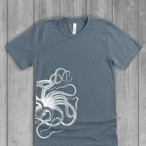 A dusty slate blue women's short-sleeve t-shirt with a white side octopus with tentacles print on the front.