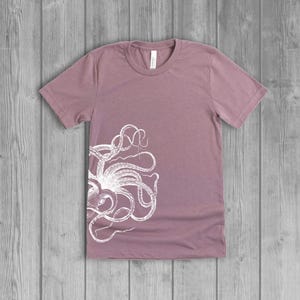 A dusty light mauve pink women's short-sleeve t-shirt with a white side octopus with tentacles print on the front.