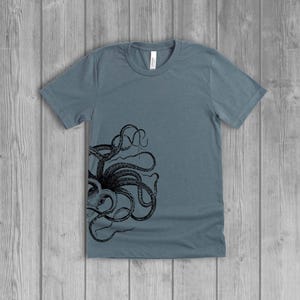 A dusty slate blue women's short-sleeve t-shirt with a black side octopus with tentacles print on the front.