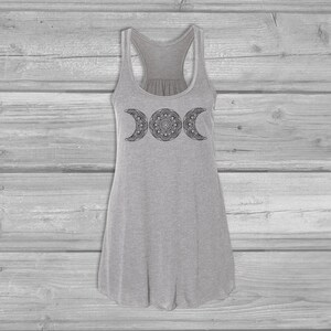 May include: A gray tank top with a black triple moon mandala design. The tank top has a racerback style and a loose fit.