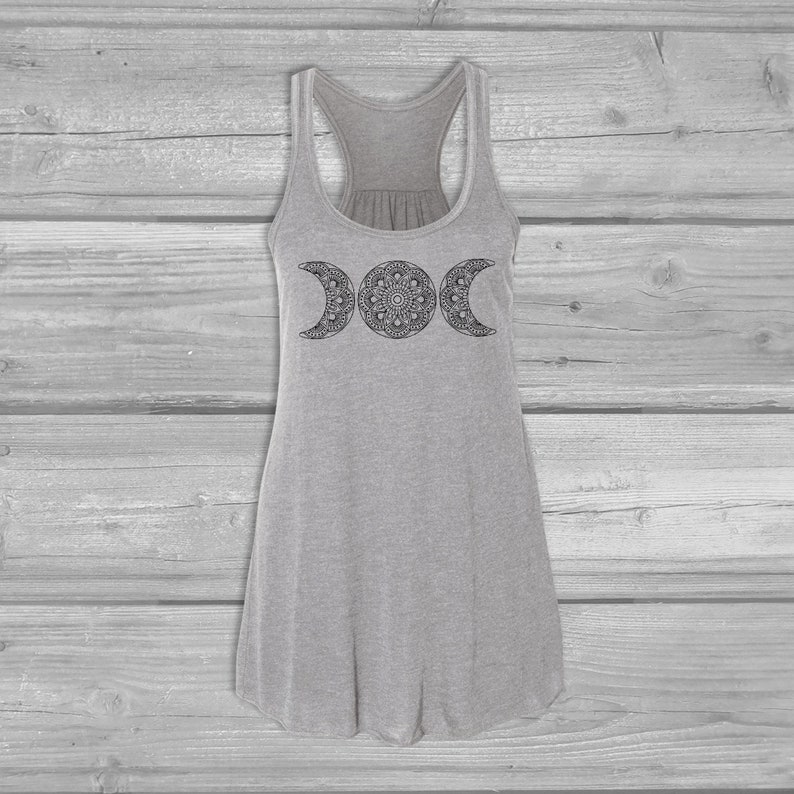 May include: A gray tank top with a black triple moon mandala design. The tank top has a racerback style and a loose fit.