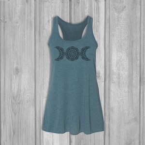 May include: A teal blue tank top with a black triple moon mandala design. The tank top is made of a soft, comfortable fabric and has a relaxed fit.