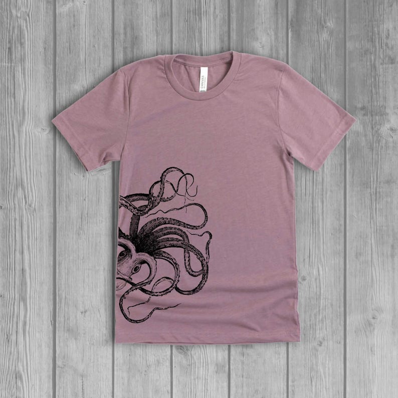 A dusty light mauve pink women's short-sleeve t-shirt with a black side octopus with tentacles print on the front.