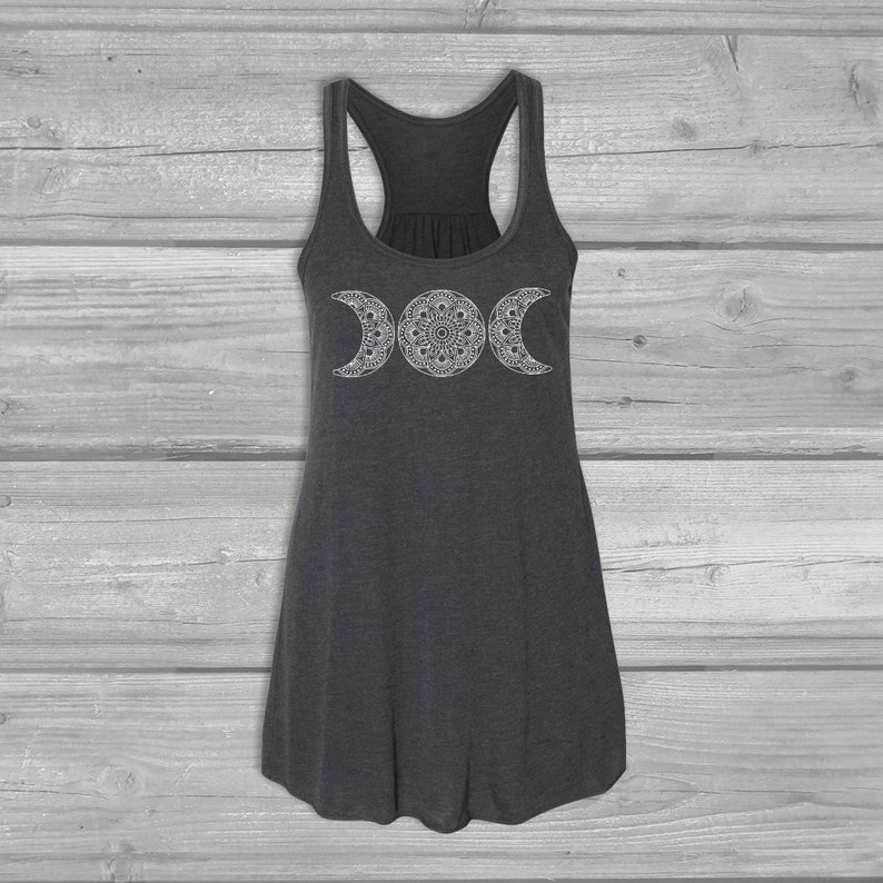 May include: A dark gray tank top with a white triple moon mandala design. The tank top has a racerback style.