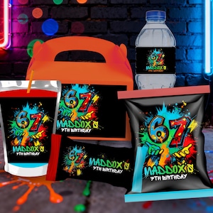 Peut inclure: Ensemble de fournitures de fête sur le thème du 67e anniversaire. Comprend une boîte cadeau orange, une poche de jus, une bouteille d'eau et des sachets de collation, tous avec le nom "Maddox" et "7th Birthday" dans un style graffiti.