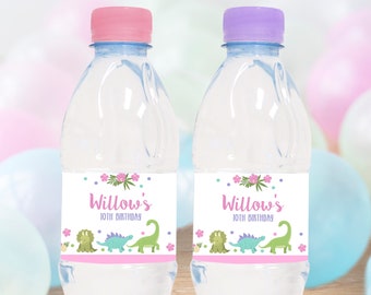 Può includere: Due bottiglie d'acqua in plastica trasparente con tappi rosa e viola. Ogni bottiglia ha un'etichetta bianca con un bordo rosa e un design di dinosauro verde. L'etichetta recita "Willow's 10th Birthday".