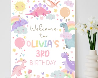 May include: A white welcome sign with a rainbow, clouds, and dinosaurs. The text reads "Welcome to Olivia's 3rd Birthday".