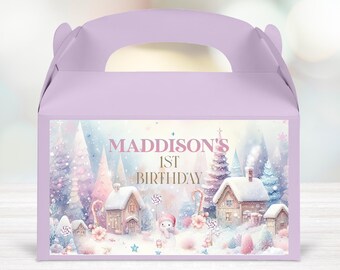 May include: A purple favor box with a handle. The front of the box has a sticker with a winter wonderland scene. The sticker says "Maddison's 1st Birthday".