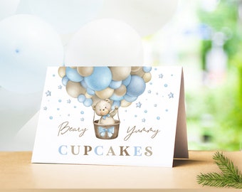 May include: A white card with a blue and brown balloon hot air balloon with a teddy bear in the basket. The card says "Beary Yummy Cupcakes".