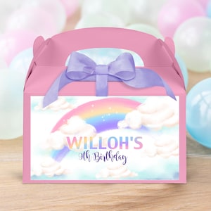 May include: Pink favor box with a purple ribbon and a rainbow design. The box has a handle and says "Willoh's 9th Birthday" on the front.