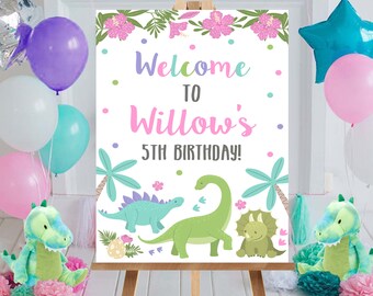 May include: Welcome to Willow's 5th Birthday! A white sign with pink, green, and blue dinosaur illustrations and tropical leaves. The sign has a welcome message and the text "Willow's 5th Birthday!"