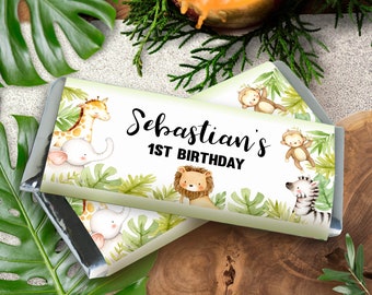 May include: Chocolate bar wrappers with a jungle theme. The wrappers feature illustrations of a giraffe, elephant, lion, zebra, and monkeys. The text "Sebastian's 1st Birthday" is displayed in black script.