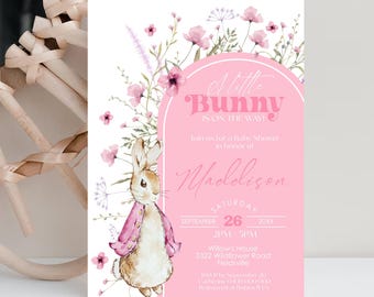 May include: Pink baby shower invitation with a watercolor illustration of a bunny wearing a pink coat and surrounded by pink flowers. The text reads "A Little Bunny Is On The Way!" and includes the name "Maddison", the date "September 26, 20XX", and the time "2PM - 5PM".