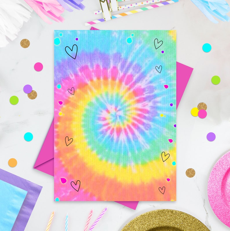 May include: A tie-dye card with a rainbow swirl pattern and black hearts. The card is on a white surface with pink, blue, and yellow confetti.