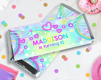 Puede incluir: Un envoltorio de barra de chocolate colorido con un diseño de neón y estrellas. El texto en el envoltorio dice "MADDISON cumple 10 años".