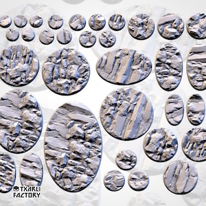 May include: A set of 20 round and oval resin bases for miniature wargaming. The bases feature a textured, rocky surface in shades of grey. The bases are designed to represent a rocky terrain.