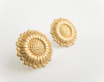 May include: A pair of gold-tone sunflower earrings. The earrings are made of metal and feature a detailed sunflower design.