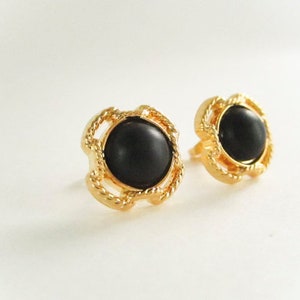 May include: A pair of gold earrings with black round stones set in a decorative gold frame.