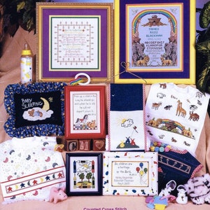 May include: A collection of cross stitch patterns for baby-themed projects. The patterns include a baby sleeping, a rainbow with animals, a child's prayer, and a child's name with a rainbow and animals. The patterns are framed and displayed with various baby-related items, including a baby bottle, a stuffed animal, and a pair of baby shoes.