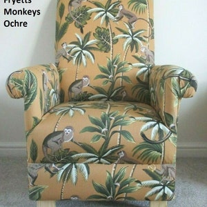 May include: An armchair upholstered in ochre fabric, adorned with a pattern of monkeys and tropical plants. The design includes palm trees and green leaves. The chair has a high back, rolled arms, and wooden legs. The text "Fryetts Monkeys Ochre" is visible.