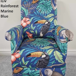 May include: Upholstered armchair with a tropical rainforest design in Marine Blue. The fabric features toucans, monkeys, and foliage in green, orange, and yellow. The chair has a high back and wooden legs.