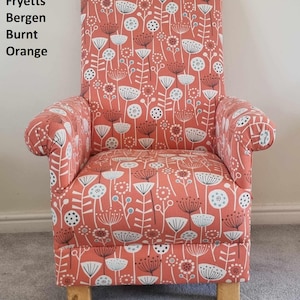May include: A burnt orange armchair with a floral pattern featuring white and grey stylised flowers. The chair has a high back and rolled arms.