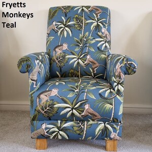 May include: Teal armchair with a tropical monkey and palm tree design. The chair has a high back, armrests, and wooden legs. The fabric features monkeys, palm trees, and foliage in brown, green, and white.