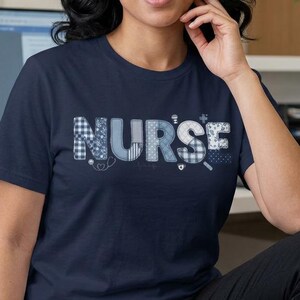Peut inclure: Un t-shirt bleu marine avec le mot "NURSE" dans un motif patchwork. Les lettres sont de différentes nuances de bleu et de blanc, avec des motifs comme le vichy et les pois. Le t-shirt est porté par une personne.