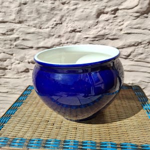 May include: A white ceramic mug with a black handle and the text "But First, Coffee" in a bold, black font. The mug is set against a blurred background, suggesting a cosy setting.