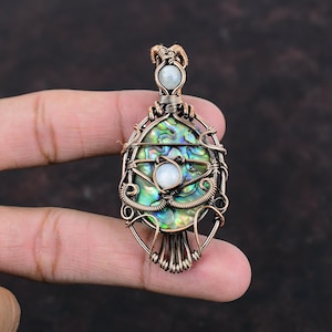 May include: A copper wire wrapped pendant featuring a green and blue abalone shell with two white iridescent stones.