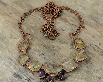 May include: A copper necklace with a chain and a pendant made of multiple raw, faceted, light yellow and amber stones. The pendant is accented with small, purple amethyst stones.
