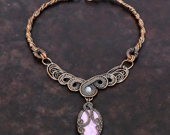 May include: A handcrafted copper wire necklace with a lavender-colored oval pendant. The necklace features intricate wirework and a twisted rope design. The pendant is approximately 1.5 inches long and is suspended from a decorative centerpiece.