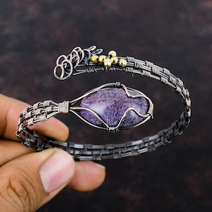 May include: A purple and silver wire wrapped bracelet with a purple stone and gold accents.
