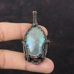 以下が含まれることがあります： 緑と虹色のオーバル型の宝石を特徴とする、銅線で巻かれたペンダント