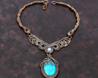 May include: A copper wire necklace with a turquoise stone pendant. The necklace has a delicate, intricate design and is a beautiful statement piece.