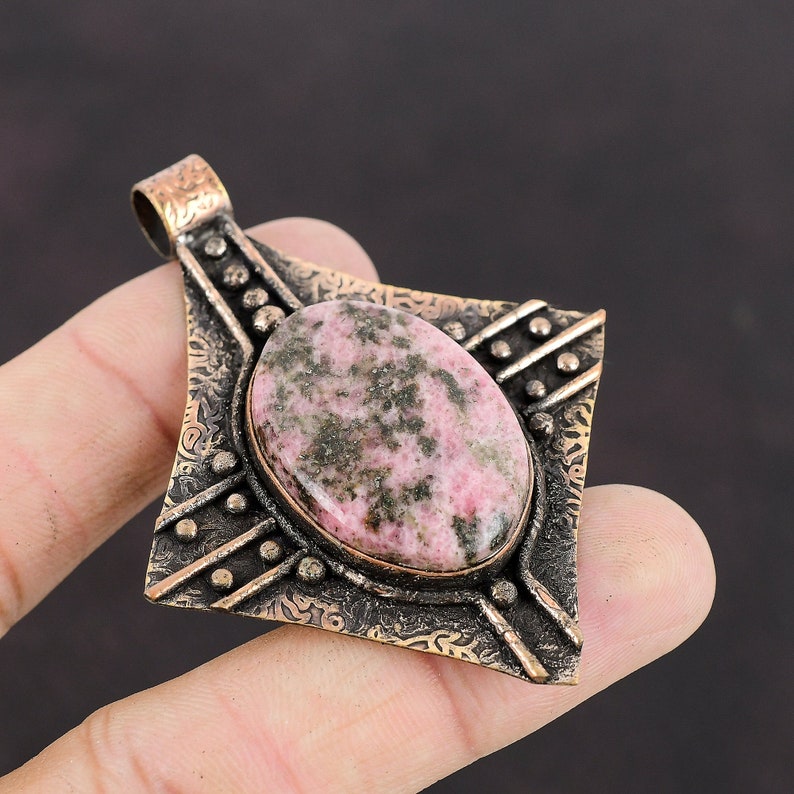 May include: A pink and green gemstone pendant with an ornate silver setting. The pendant is shaped like a diamond and has a detailed design.