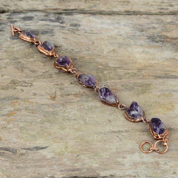 Raw amethyst crystal encased in intricate electroformed copper — a wearable geology experiment where the metal literally grows around the stone.