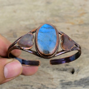 May include: Copper bracelet with a blue labradorite gemstone and two heart-shaped accents.
