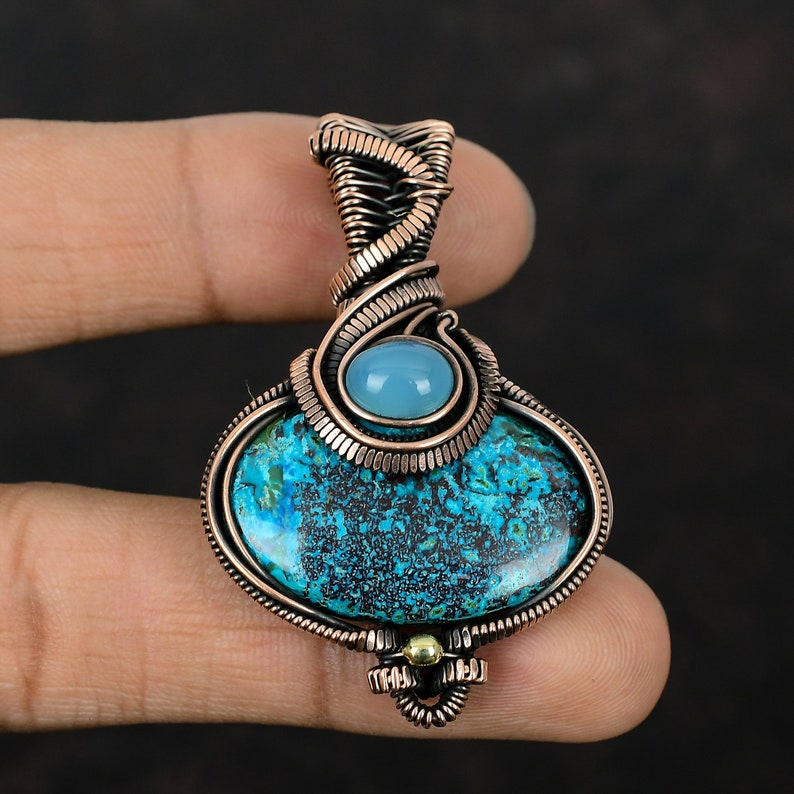 May include: A copper wire wrapped pendant featuring a blue and green gemstone with a smaller light blue gemstone at the top.