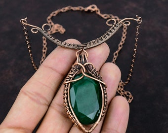 May include: A copper wire wrapped pendant necklace with a large, faceted, dark green gemstone. The necklace has a delicate copper chain.