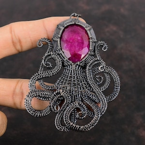 May include: A silver wire-wrapped octopus pendant with a large, faceted, pink gemstone in the center.