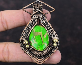 May include: A green and gold gemstone pendant with a copper wire frame. The pendant is shaped like a diamond and has a square loop at the top for attaching a chain.