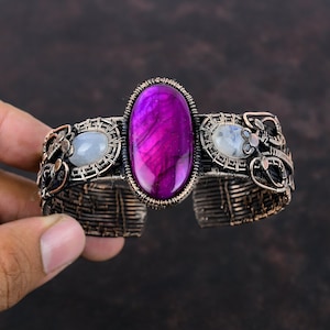 May include: A copper wire wrapped bracelet with a large oval purple agate gemstone and two smaller white moonstone gemstones.